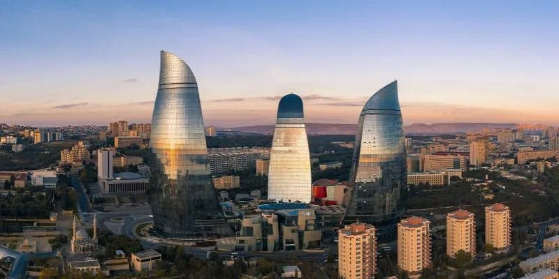 Aerial view of Baku at sunset, showcasing the Flame Towers with their reflective glass surfaces