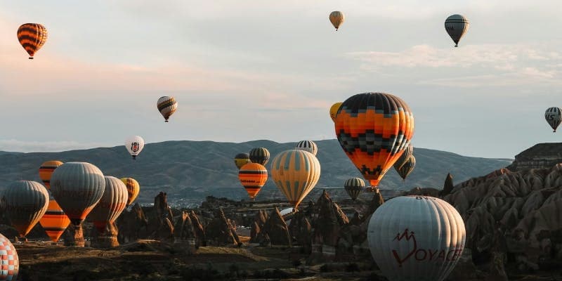 Colorful hot air balloons flying over the rocky landscape of Cappadocia.