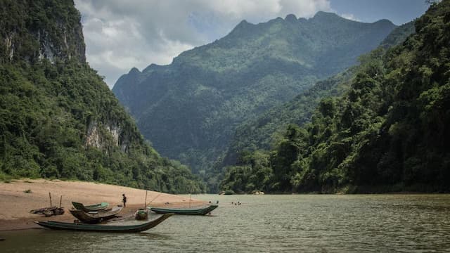 Mountainous river landscape with wooden boats.