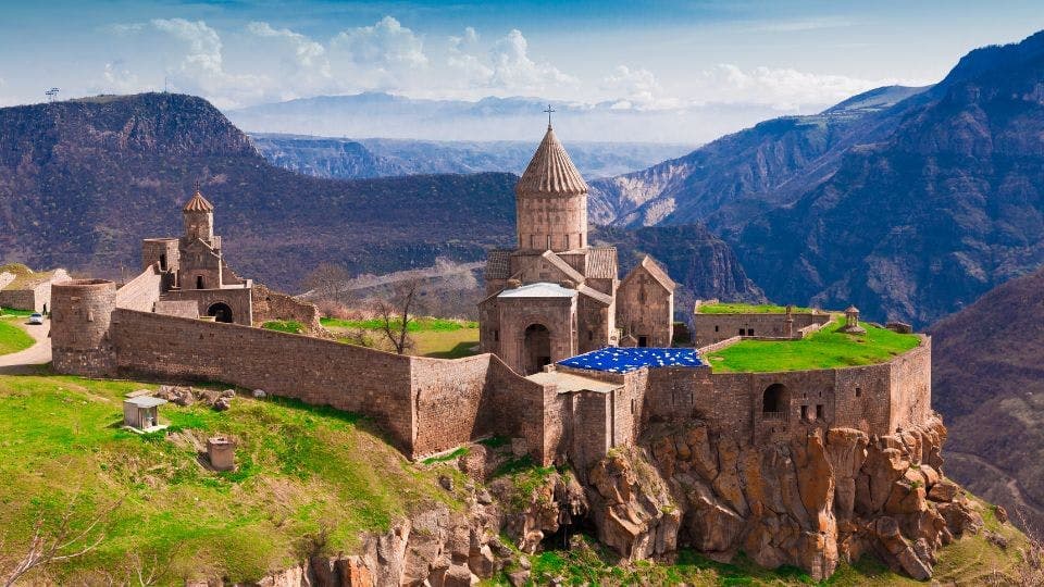 Ancient Armenian monastery with mountain backdrop.