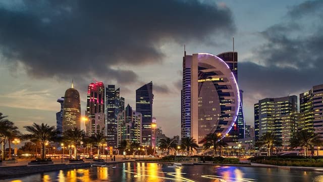 Doha city skyline illuminated at dusk.